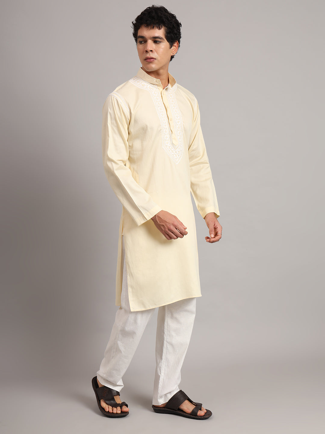 Modelled Uman men's kurta with a straight body, side slits and long sleeves, featuring concentrated Chikankari detailing around the mandarin collar and upper chest.