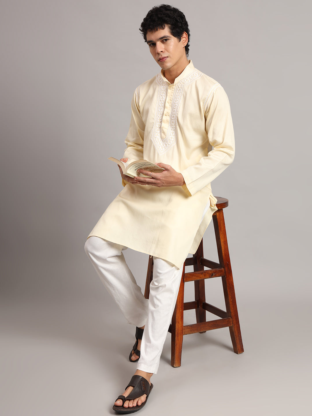Studio photograph of the Uman Mens Kurta showing its front buttons, structured collar and narrow shoulder embroidery, with the model standing upright facing the camera.