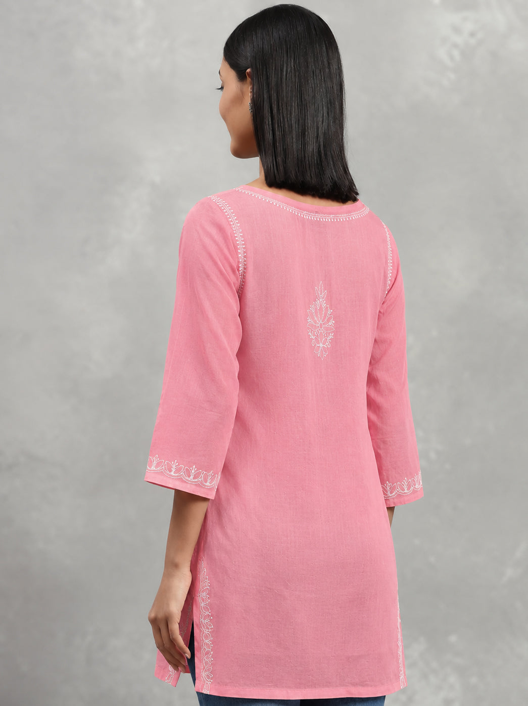 Everyday cotton Chikankari kurti displayed on a hanger, highlighting its short silhouette, three-quarter sleeves and floral embroidery across the front.