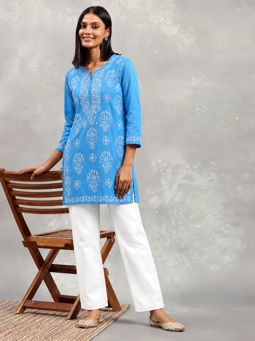 Cotton Chikankari kurti with an elongated embroidered neckline panel, alternating floral motifs across the front and a decorative border along the lower hem.