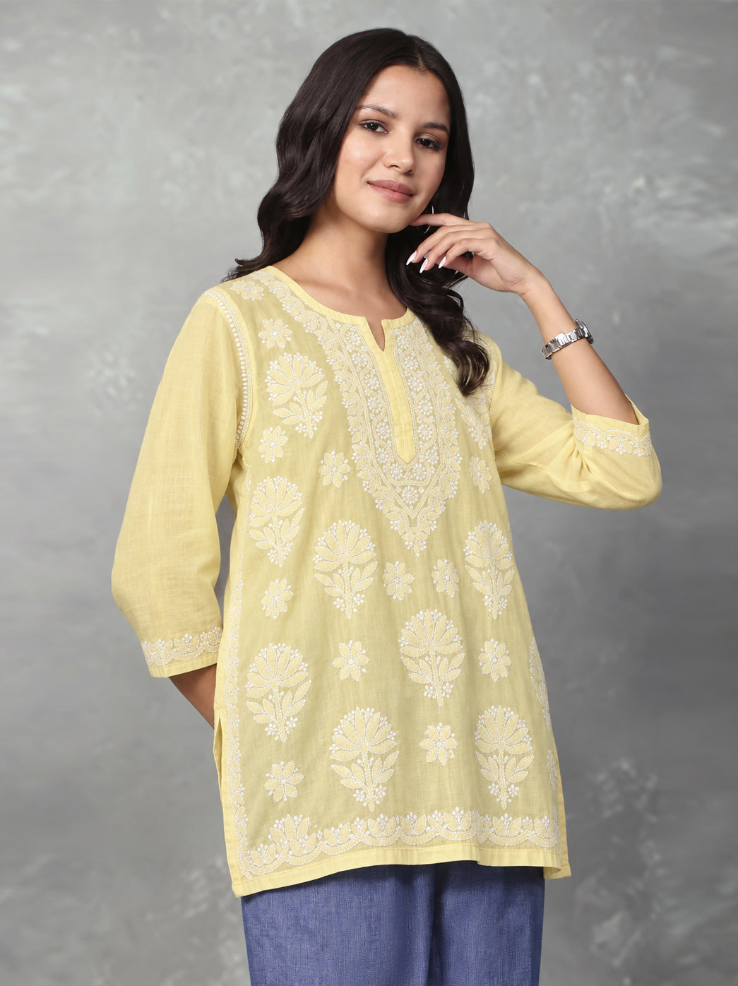 Front view of the Ziva Cotton Short Kurti showing scattered floral motifs, an intricately embroidered neckline and decorative detailing along the hem.

