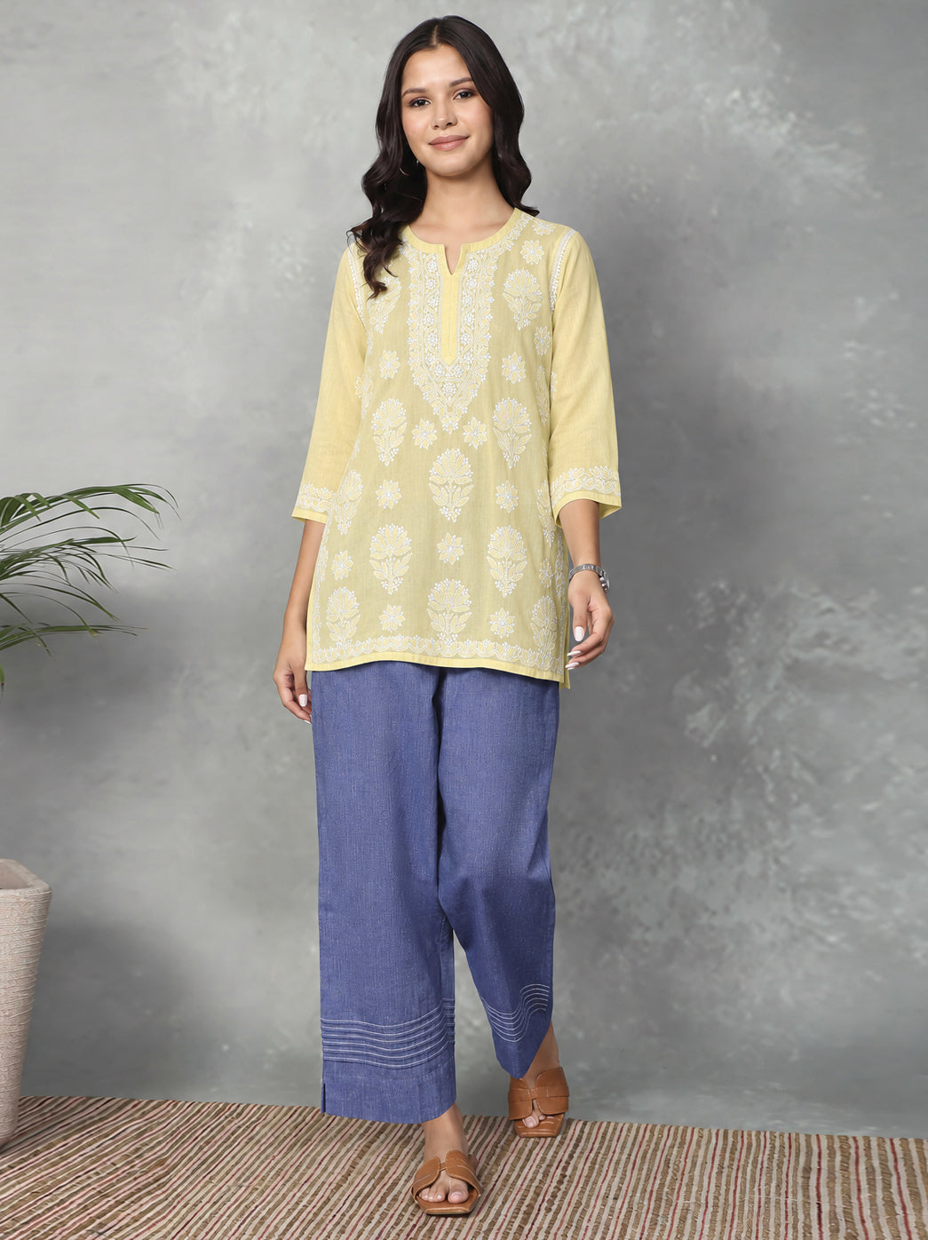 Cotton Chikankari kurti with an elongated embroidered neckline panel, alternating floral motifs across the front and a decorative border along the lower hem.