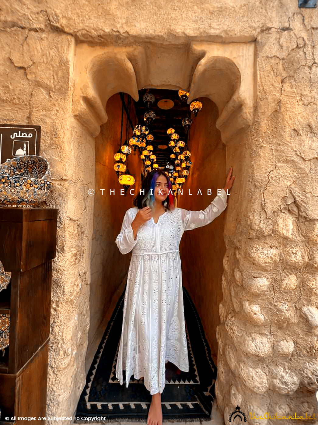 Woman wearing Naazni Viscose Chikankari Anarkali in white, standing barefoot in a heritage archway
