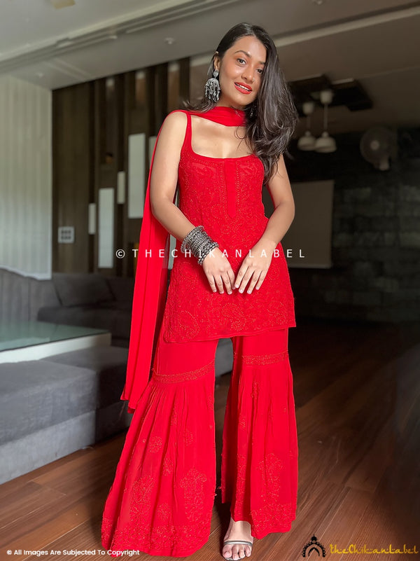 Woman wearing red chikankari strappy kurta set with matching sharara and dupatta styled for festive celebration